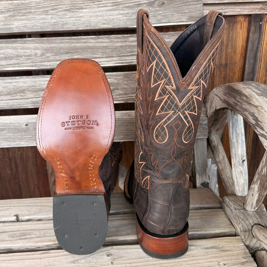 Brown cowboy boot with intricate stitching on a wooden surface, featuring the Stetson brand.
