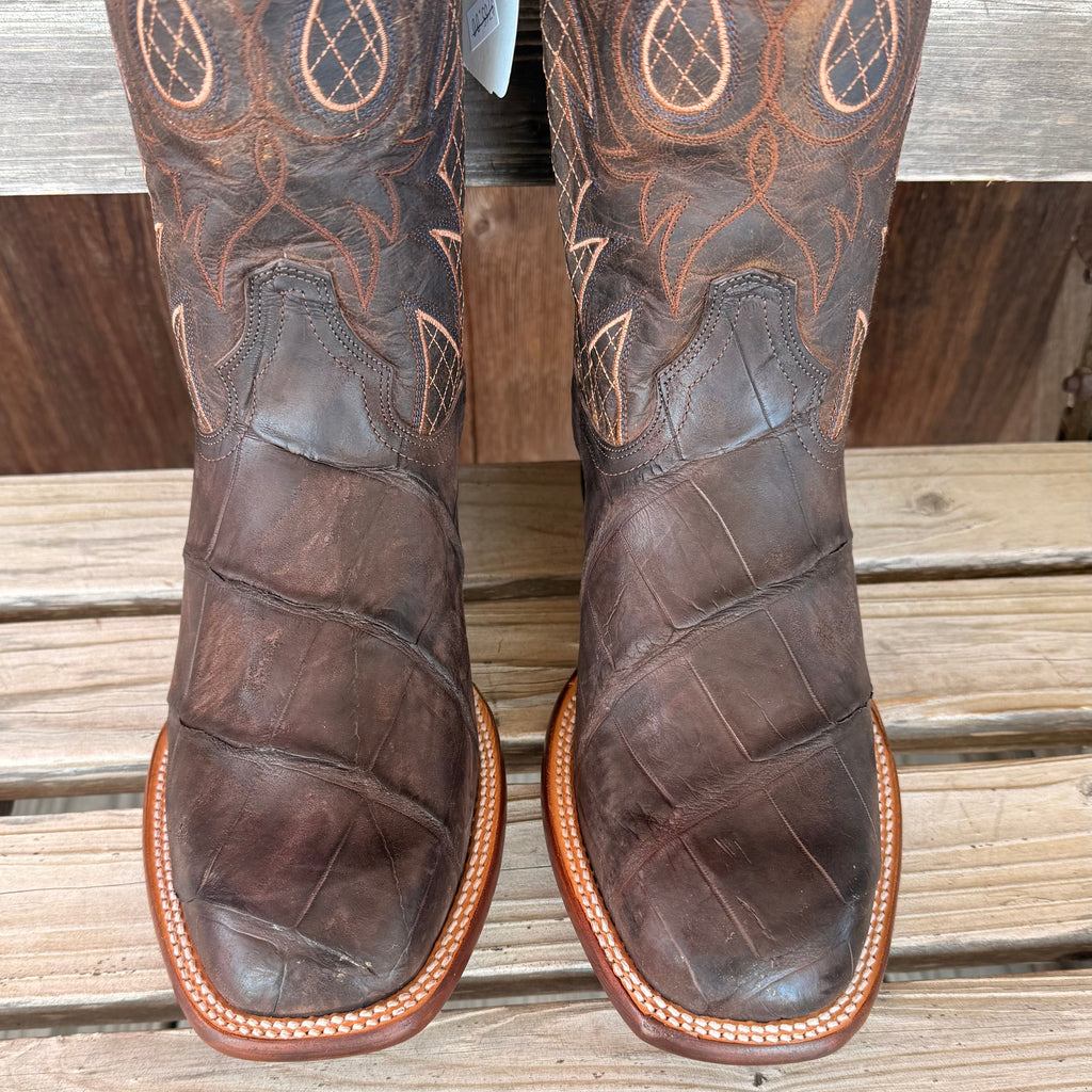 Brown leather boots with intricate stitching on a wooden surface