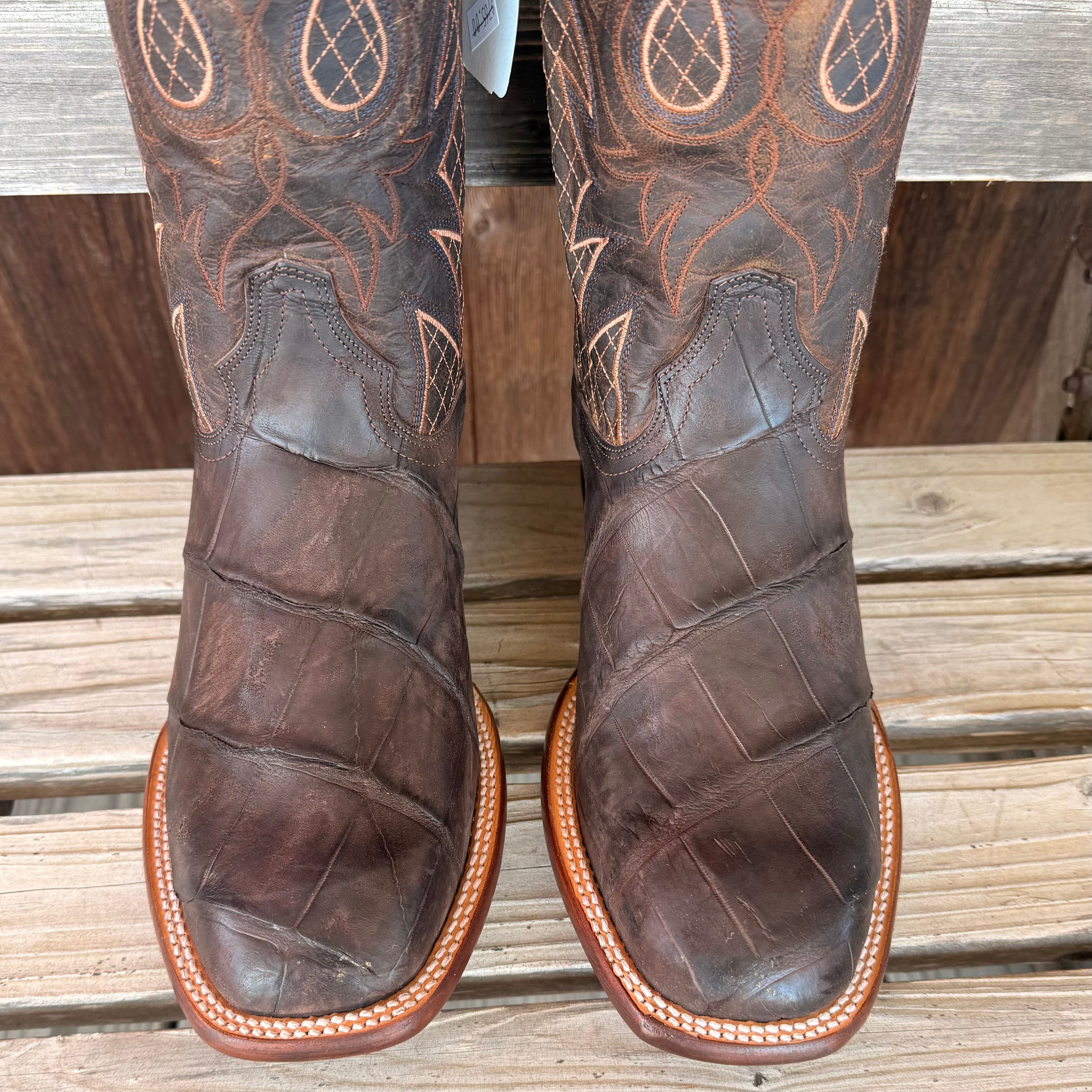 Brown leather boots with intricate stitching on a wooden surface