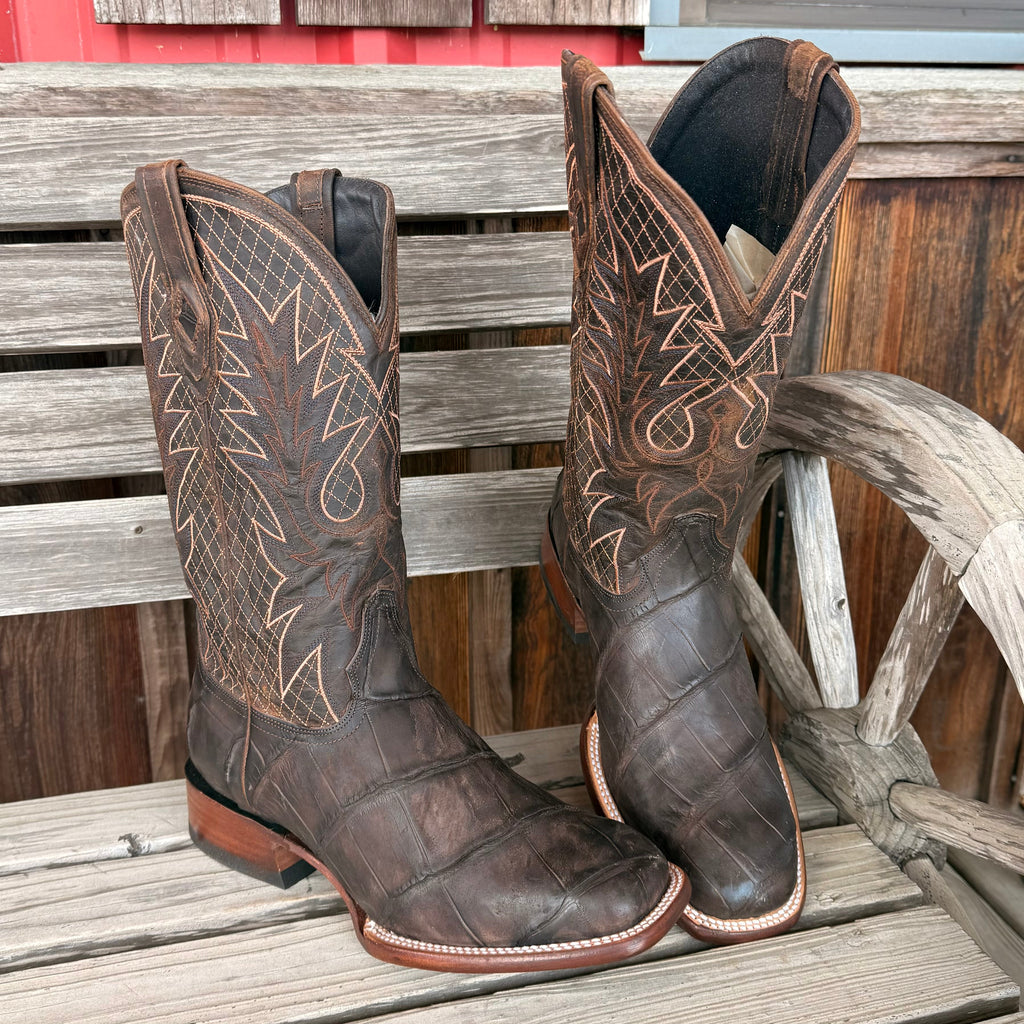 Pair of brown cowboy boots with intricate designs on a wooden surface