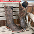 Pair of brown cowboy boots with intricate designs on a wooden surface
