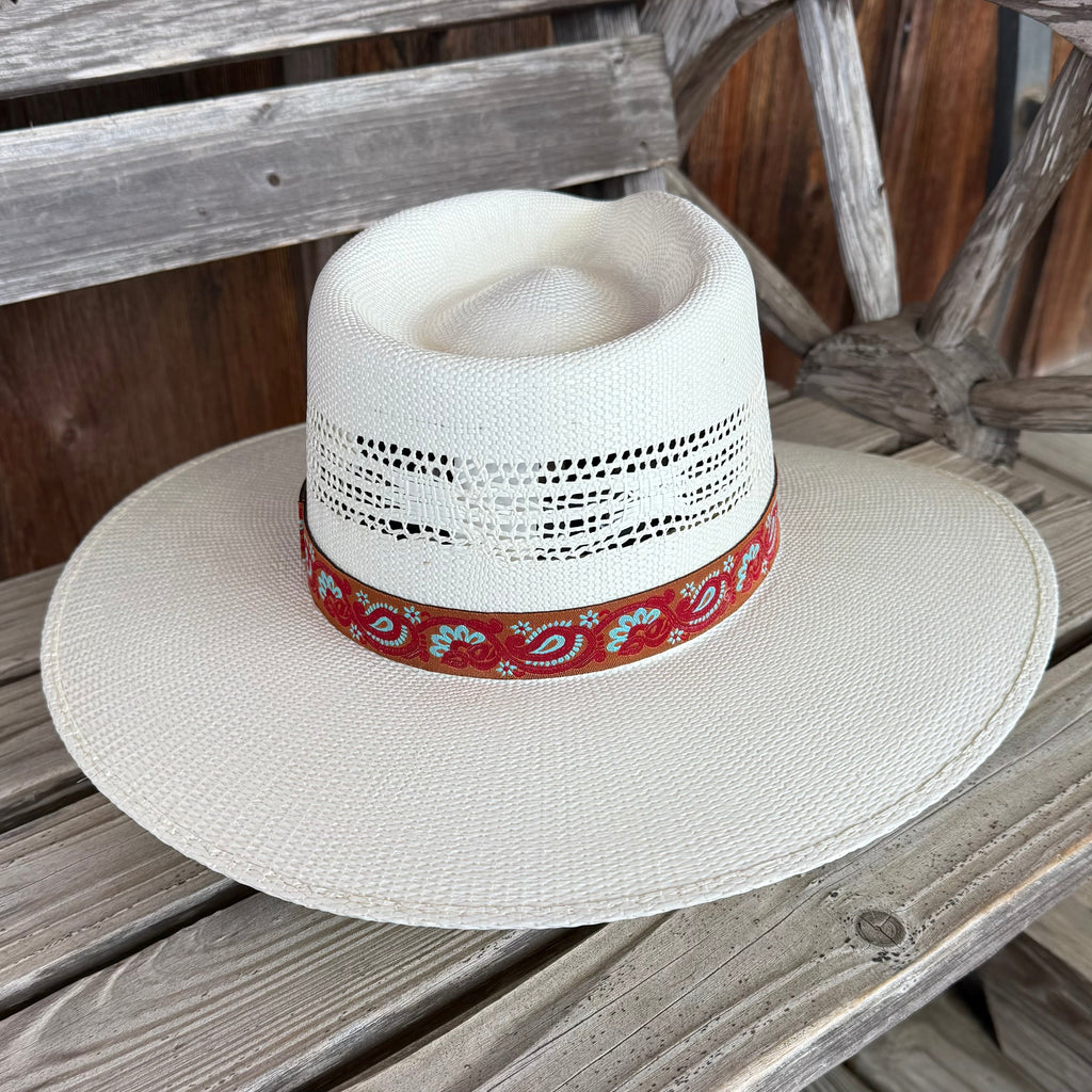White straw hat with a red bandana on a wooden surface
