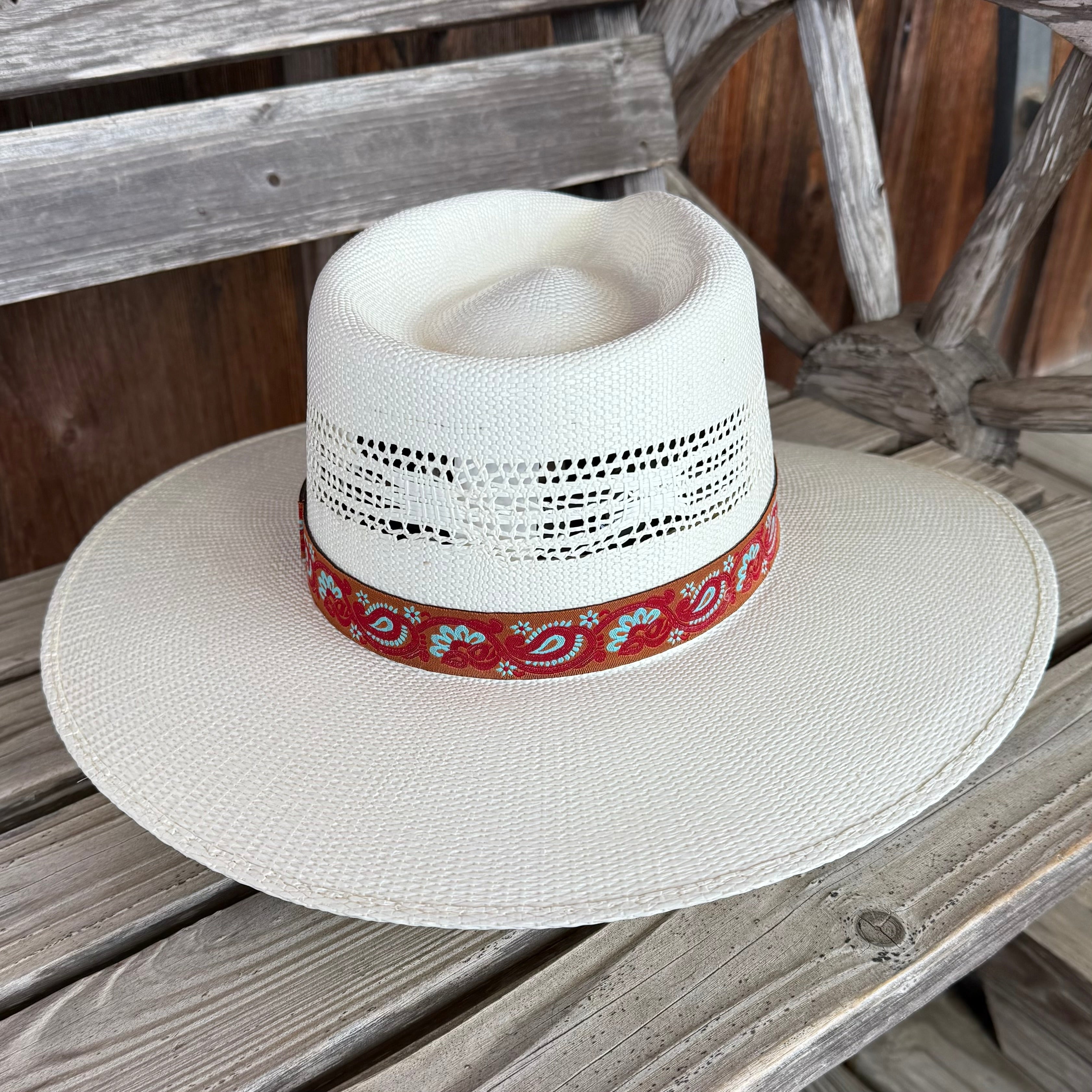 White straw hat with a red bandana on a wooden surface