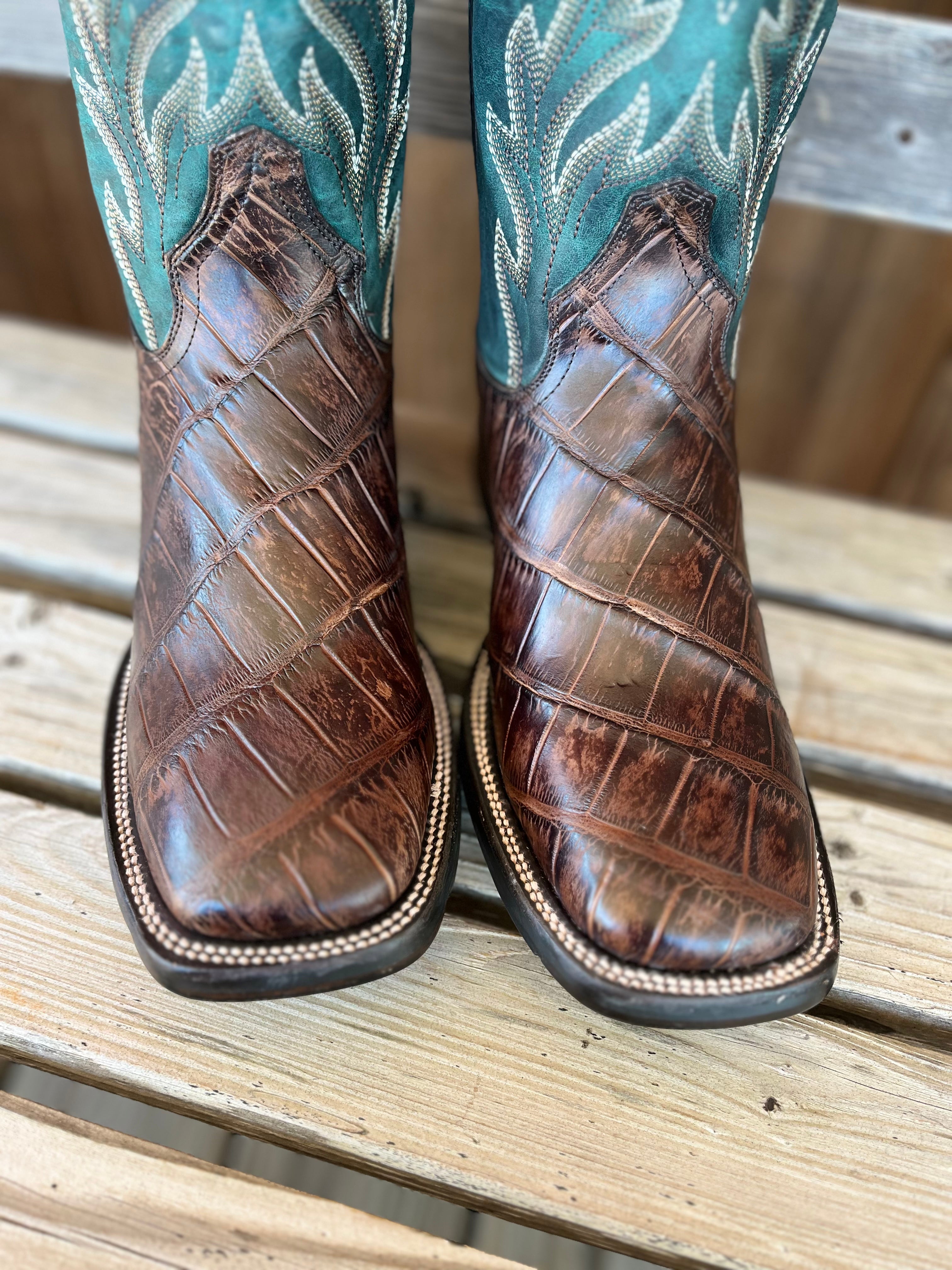 Brown cowboy boots with turquoise leather uppers on a wooden surface