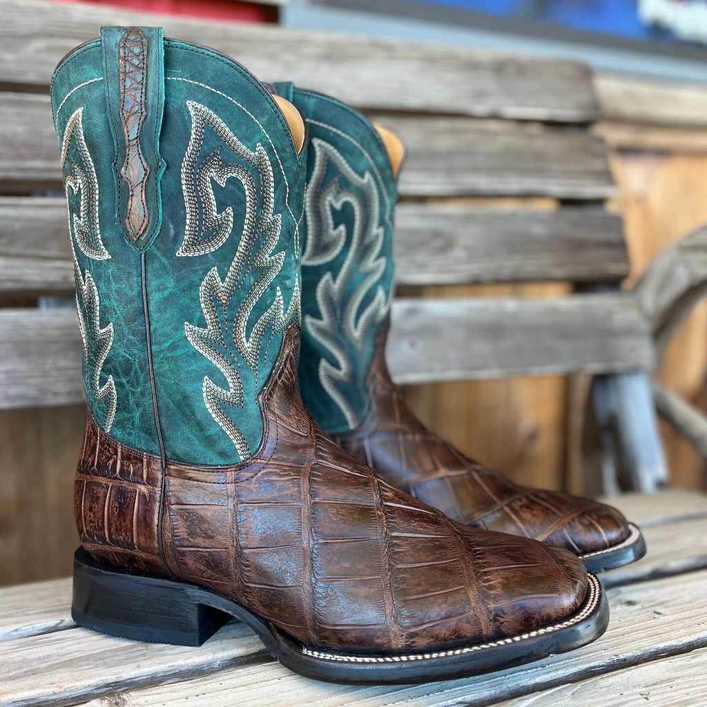 Pair of brown and teal cowboy boots on a wooden surface.